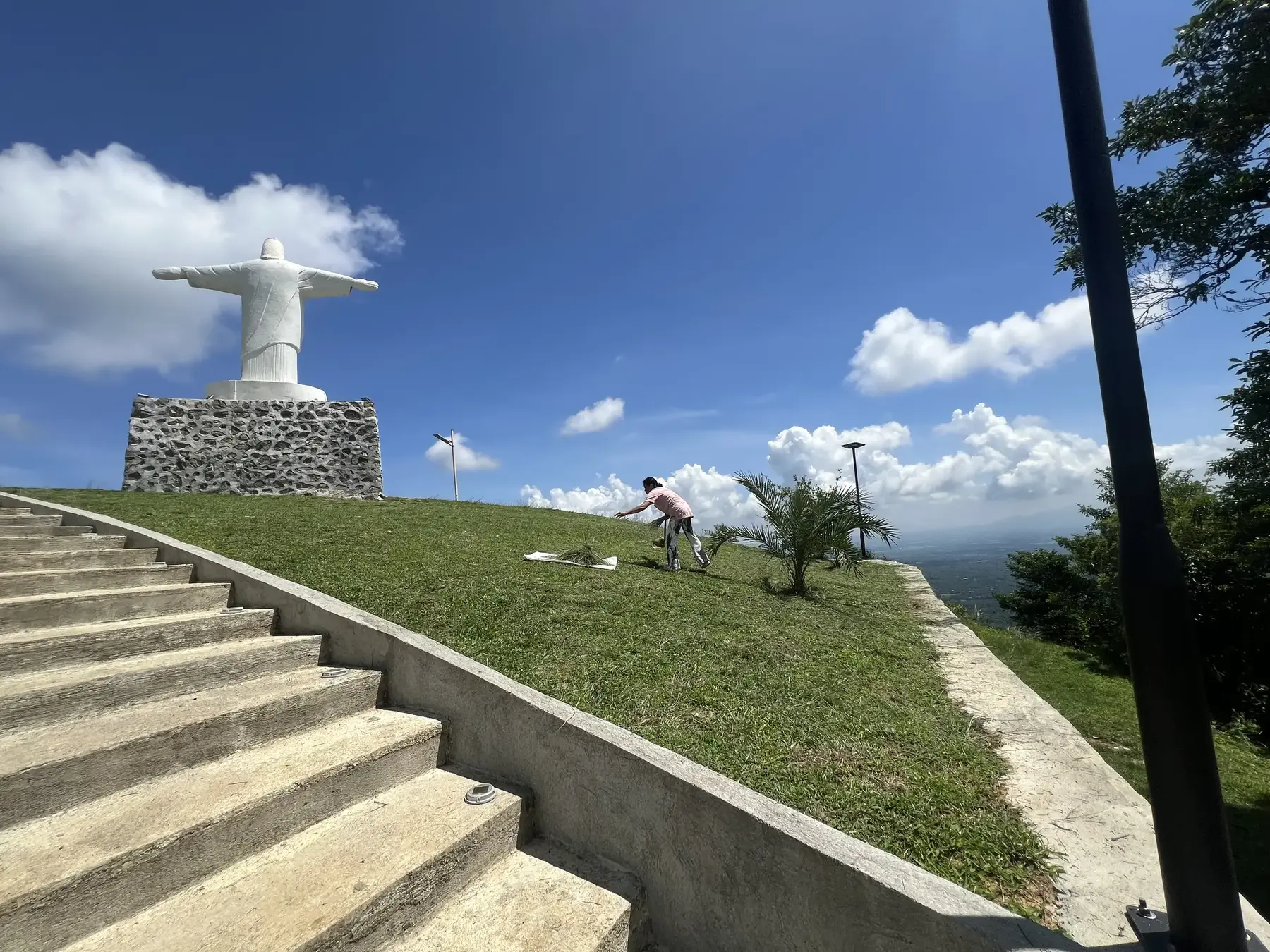 A white Christ statue on a stone pedestal at the Monte Cristo viewing deck, reached by wide concrete stairs