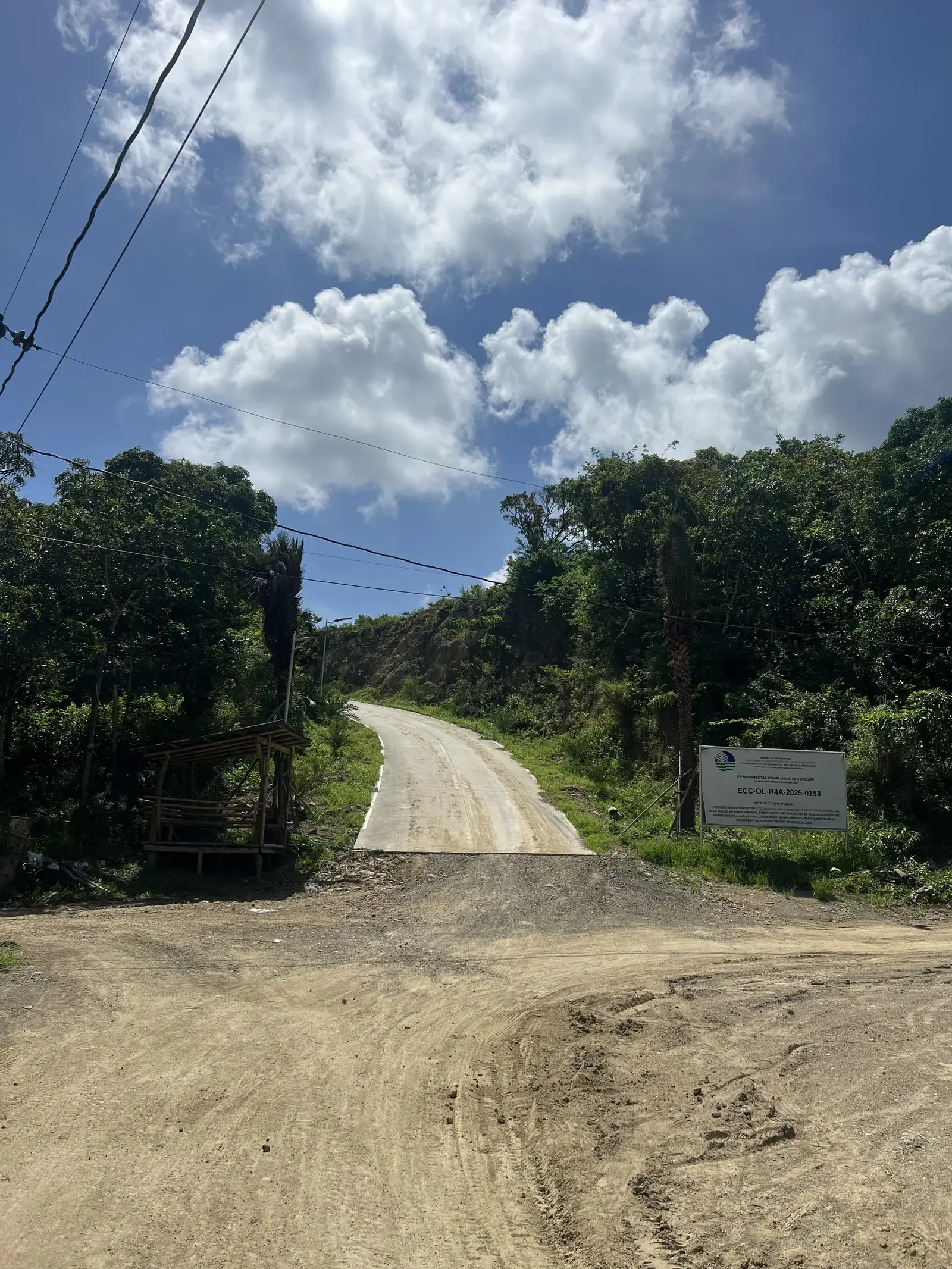 Main entrance road into Sto. Domingo Highlands with DENR project signage posted at the gate