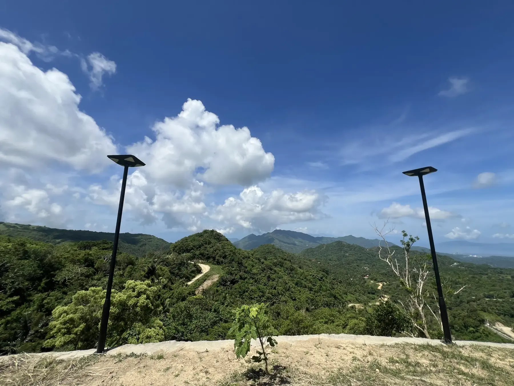 Dirt access road cutting along the ridgeline at Sto. Domingo Highlands, hills and distant broadcast towers in view